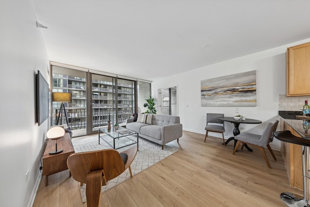 living room featuring light wood-type flooring and floor to ceiling windows