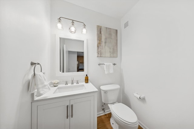 bathroom with hardwood / wood-style floors, vanity, and toilet