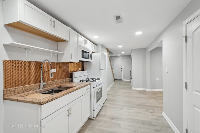 kitchen featuring white cabinetry, backsplash, sink, white appliances, and light hardwood / wood-style flooring