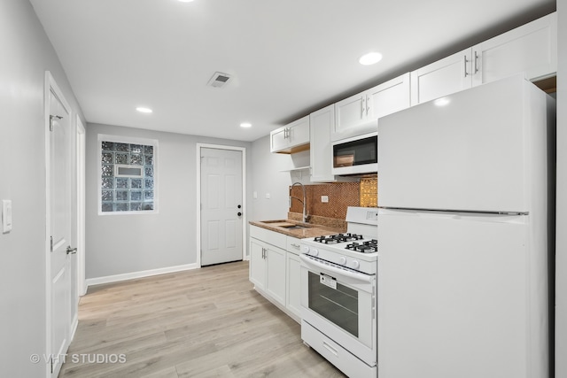 kitchen featuring white cabinetry, sink, backsplash, white appliances, and light wood-type flooring