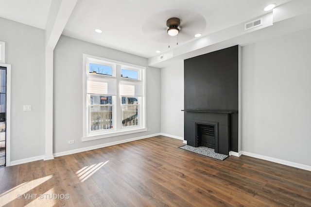 unfurnished living room featuring dark wood-type flooring and ceiling fan