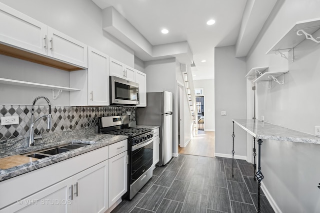 kitchen featuring appliances with stainless steel finishes, dark hardwood / wood-style flooring, decorative backsplash, sink, and white cabinets