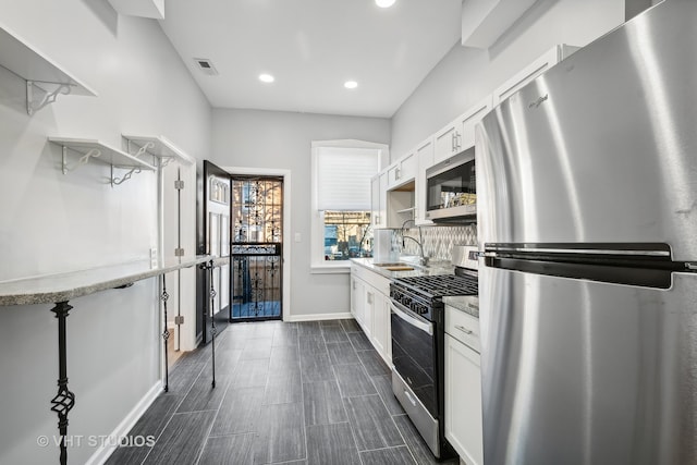 kitchen featuring white cabinets, stainless steel appliances, sink, and light stone countertops