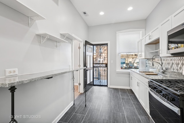 kitchen featuring white cabinetry, sink, light stone counters, appliances with stainless steel finishes, and backsplash