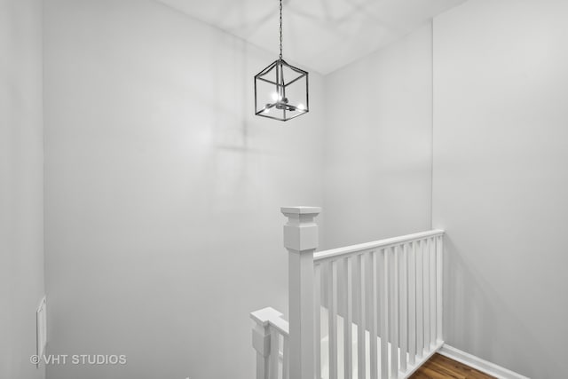 stairway with an inviting chandelier and hardwood / wood-style floors