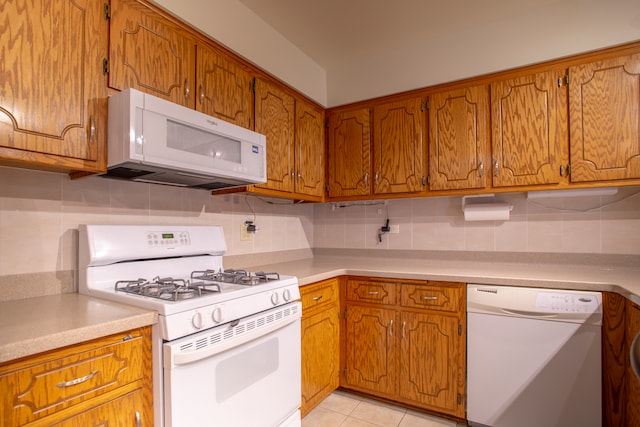 kitchen featuring tasteful backsplash, white appliances, and light tile patterned floors