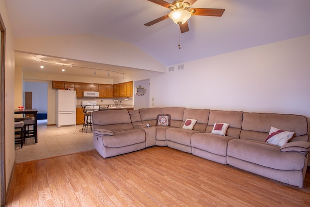 living room with sink, ceiling fan, rail lighting, lofted ceiling, and light wood-type flooring