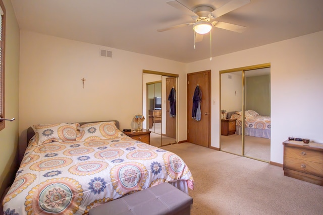 carpeted bedroom featuring ceiling fan and two closets