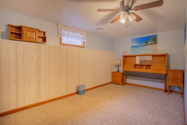 bedroom featuring ceiling fan, wooden walls, and light colored carpet