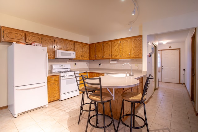 kitchen with a kitchen breakfast bar, white appliances, light tile patterned floors, and kitchen peninsula