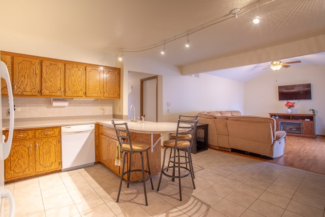 kitchen with kitchen peninsula, ceiling fan, a breakfast bar area, light wood-type flooring, and dishwasher