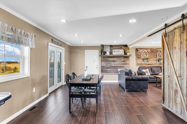 dining space featuring a barn door, dark hardwood / wood-style floors, and crown molding