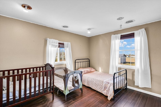 bedroom with dark hardwood / wood-style floors and multiple windows