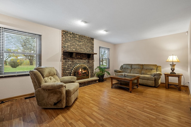 living room featuring hardwood / wood-style floors, a textured ceiling, and a brick fireplace