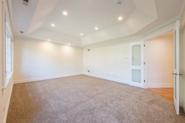 carpeted spare room with crown molding and a tray ceiling