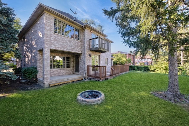 back of house featuring a wooden deck, a lawn, a fire pit, and a balcony