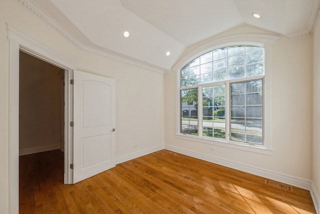 unfurnished room featuring hardwood / wood-style flooring, crown molding, and lofted ceiling