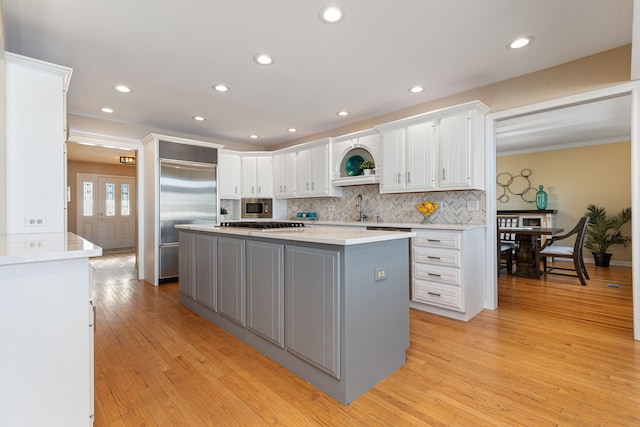 kitchen featuring built in appliances, white cabinets, a kitchen island, and tasteful backsplash