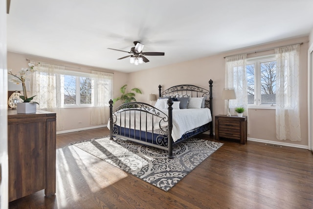 bedroom featuring ceiling fan, multiple windows, and dark hardwood / wood-style floors