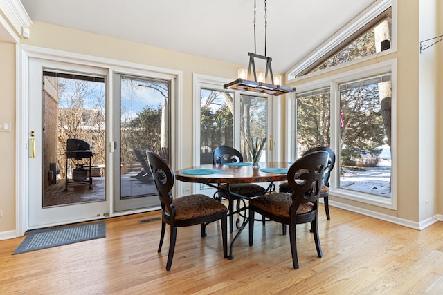 dining space featuring light wood-type flooring, vaulted ceiling, and an inviting chandelier