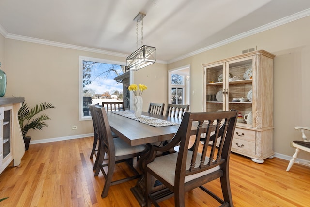 dining area featuring a chandelier, light wood-type flooring, and crown molding