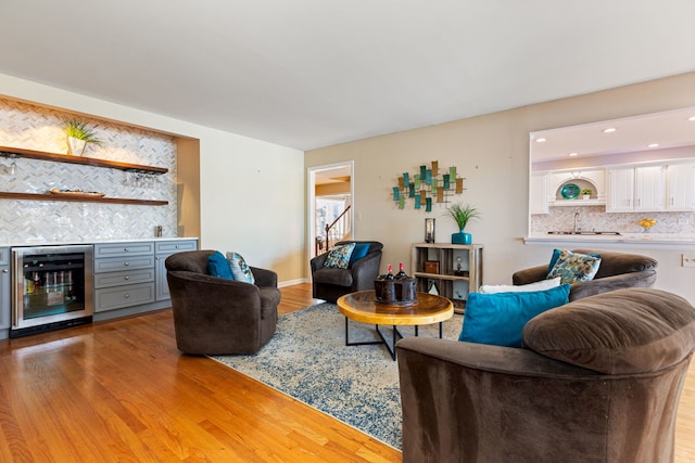 living room featuring beverage cooler, light wood-type flooring, and sink