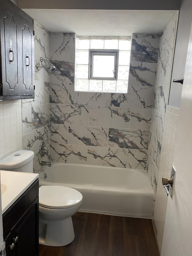 full bathroom featuring wood-type flooring, toilet, vanity, tile walls, and tiled shower / bath