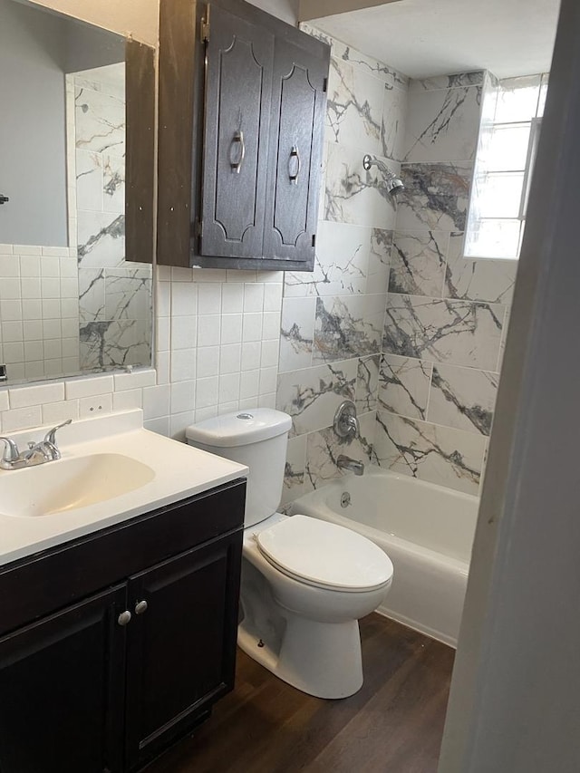 full bathroom featuring vanity, tile walls, hardwood / wood-style floors, toilet, and tiled shower / bath