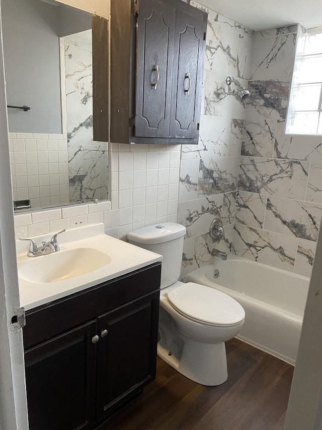 full bathroom featuring vanity, washtub / shower combination, hardwood / wood-style flooring, toilet, and tile walls