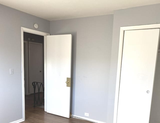 unfurnished bedroom with dark hardwood / wood-style floors and a closet