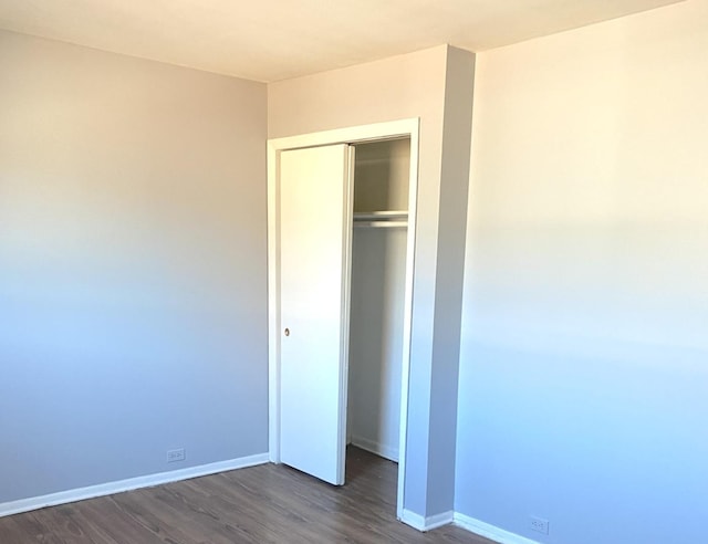 unfurnished bedroom featuring dark hardwood / wood-style flooring and a closet