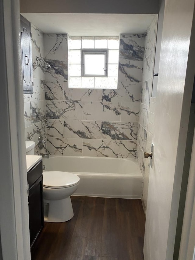 full bathroom with tiled shower / bath, toilet, vanity, and hardwood / wood-style flooring