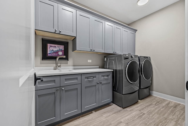 laundry area featuring light hardwood / wood-style floors, sink, cabinets, and independent washer and dryer