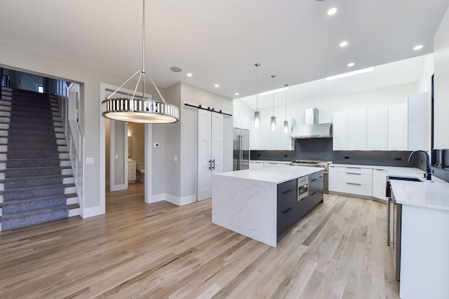 kitchen featuring a center island, sink, hanging light fixtures, a barn door, and white cabinetry