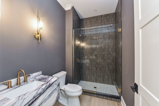 bathroom featuring crown molding, hardwood / wood-style floors, toilet, a shower with door, and vanity