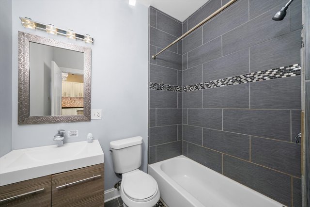 full bathroom featuring toilet, vanity, and tiled shower / bath