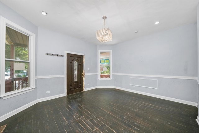 unfurnished room featuring dark hardwood / wood-style floors, plenty of natural light, and a notable chandelier