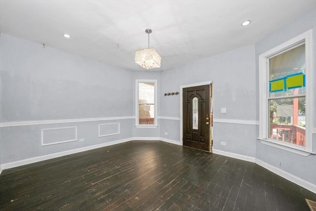 spare room featuring an inviting chandelier, dark hardwood / wood-style floors, and plenty of natural light