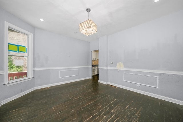 unfurnished room with dark wood-type flooring and an inviting chandelier