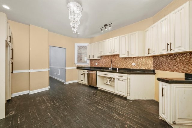 kitchen featuring dishwasher, white cabinets, a chandelier, sink, and backsplash