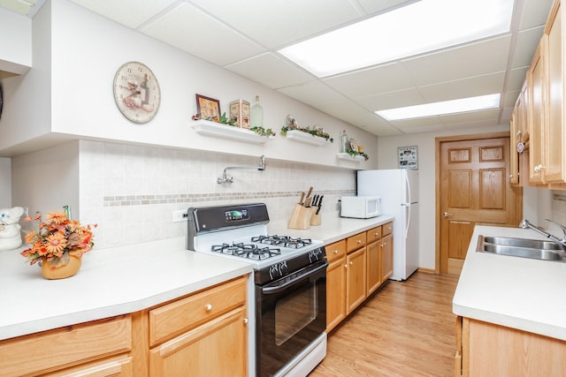 kitchen with a drop ceiling, white appliances, sink, tasteful backsplash, and light hardwood / wood-style floors