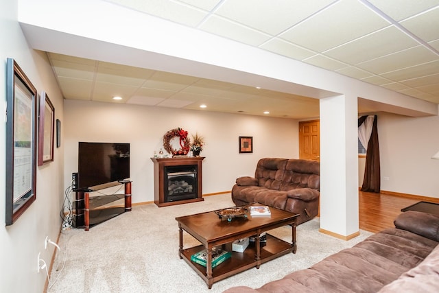 living room featuring a drop ceiling and carpet