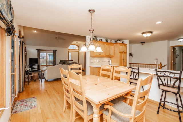 dining room with ceiling fan with notable chandelier and light hardwood / wood-style flooring