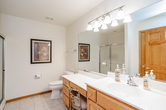 bathroom featuring tile patterned flooring, vanity, a shower with shower door, and toilet