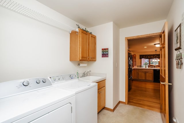 washroom featuring washer and dryer, cabinets, sink, and light hardwood / wood-style flooring