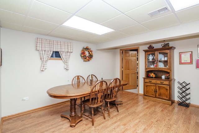 dining space with a paneled ceiling and light wood-type flooring