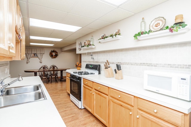 kitchen with white appliances, light hardwood / wood-style floors, a paneled ceiling, and sink