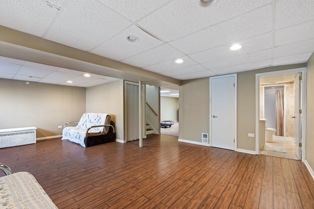 unfurnished room with dark hardwood / wood-style flooring, radiator, and a drop ceiling