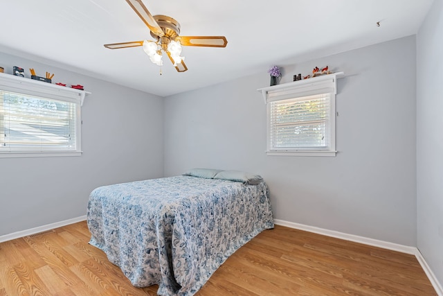 bedroom featuring multiple windows, wood-type flooring, and ceiling fan