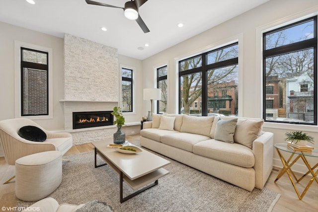 living room featuring a fireplace, light hardwood / wood-style flooring, and ceiling fan